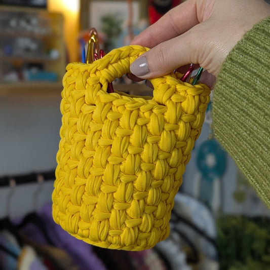 Yellow woven basket held by a hand with a blurred indoor background